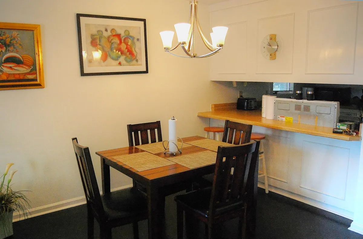 A warm and inviting dining area with a central dining table, a modern chandelier overhead, and tasteful wall art in the background. The setup feels ready for family meals, celebrations, and shared moments, reinforcing the space’s role as a social hub.