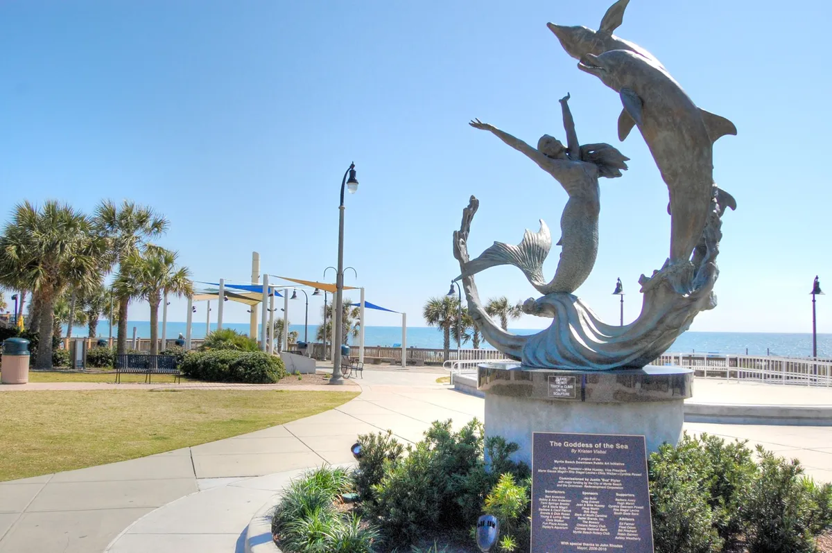 An inviting oceanfront promenade featuring the impressive sculpture of the Goddess of the Sea, with palm trees and sweeping views of the Atlantic. The image evokes a sense of tranquility and coastal enjoyment, perfect for leisurely strolls.