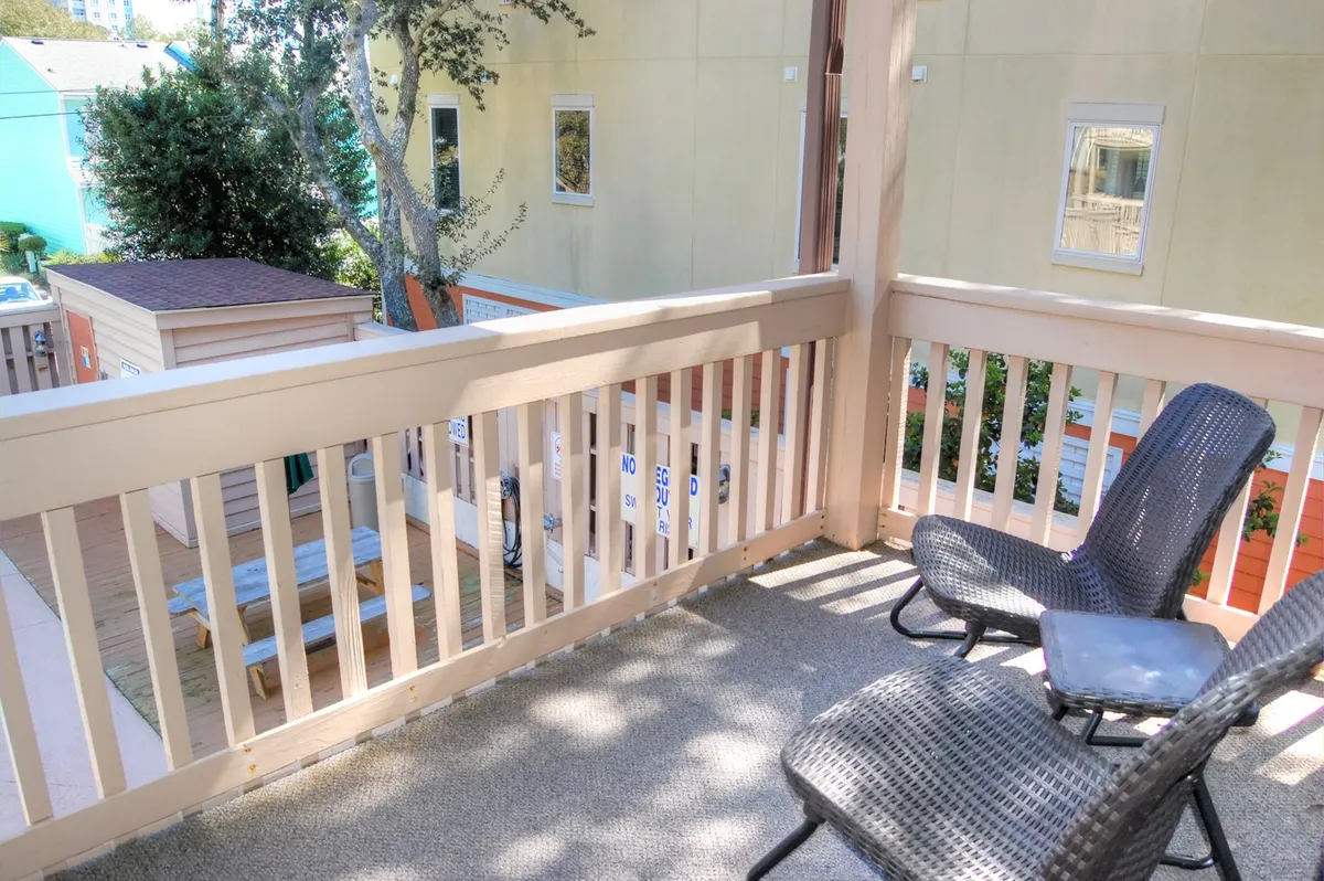This image features a tranquil private balcony with outdoor seating and a view of surrounding greenery. The balcony includes a railing and is styled for relaxation, perfect for enjoying morning coffee, quiet moments with nature, or sunset views.