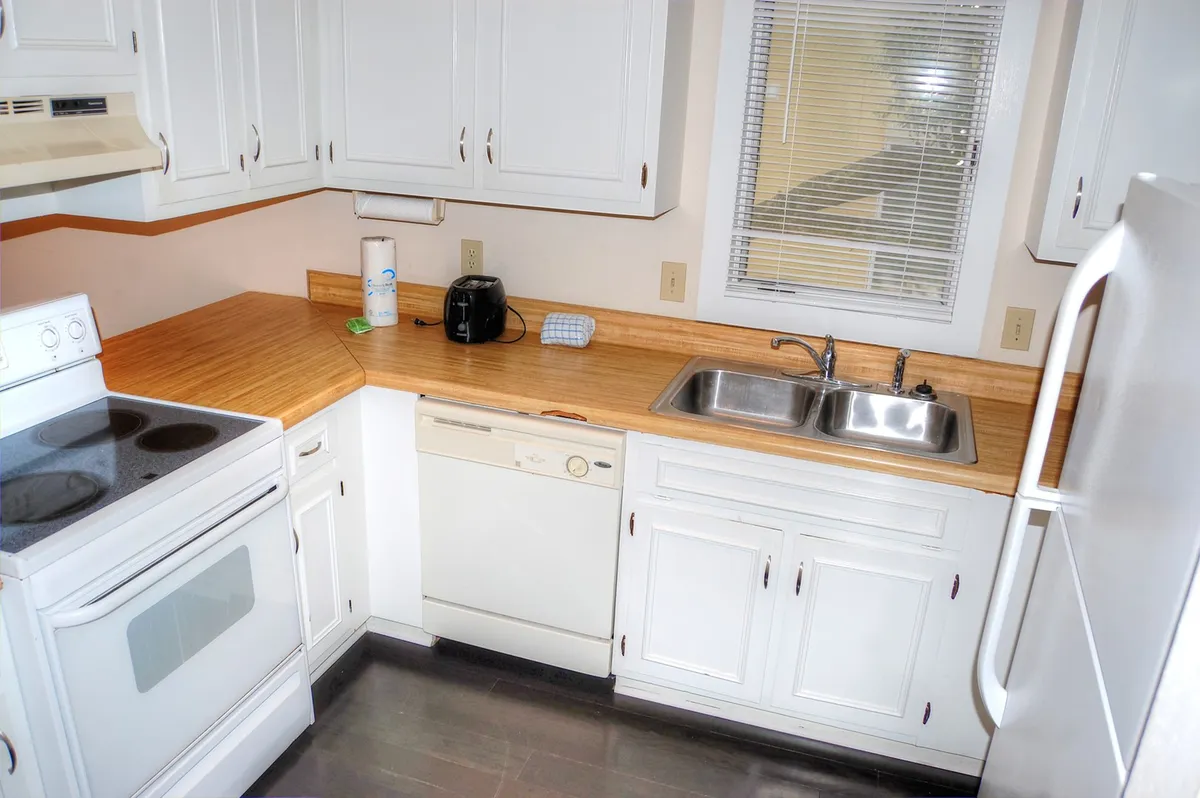 This image prominently features the kitchen area, showcasing modern appliances, ample countertop space, and a window that brings in natural light. The scene hints at recent or ongoing meal preparation, with a welcoming, homey vibe perfect for gatherings or casual cooking.