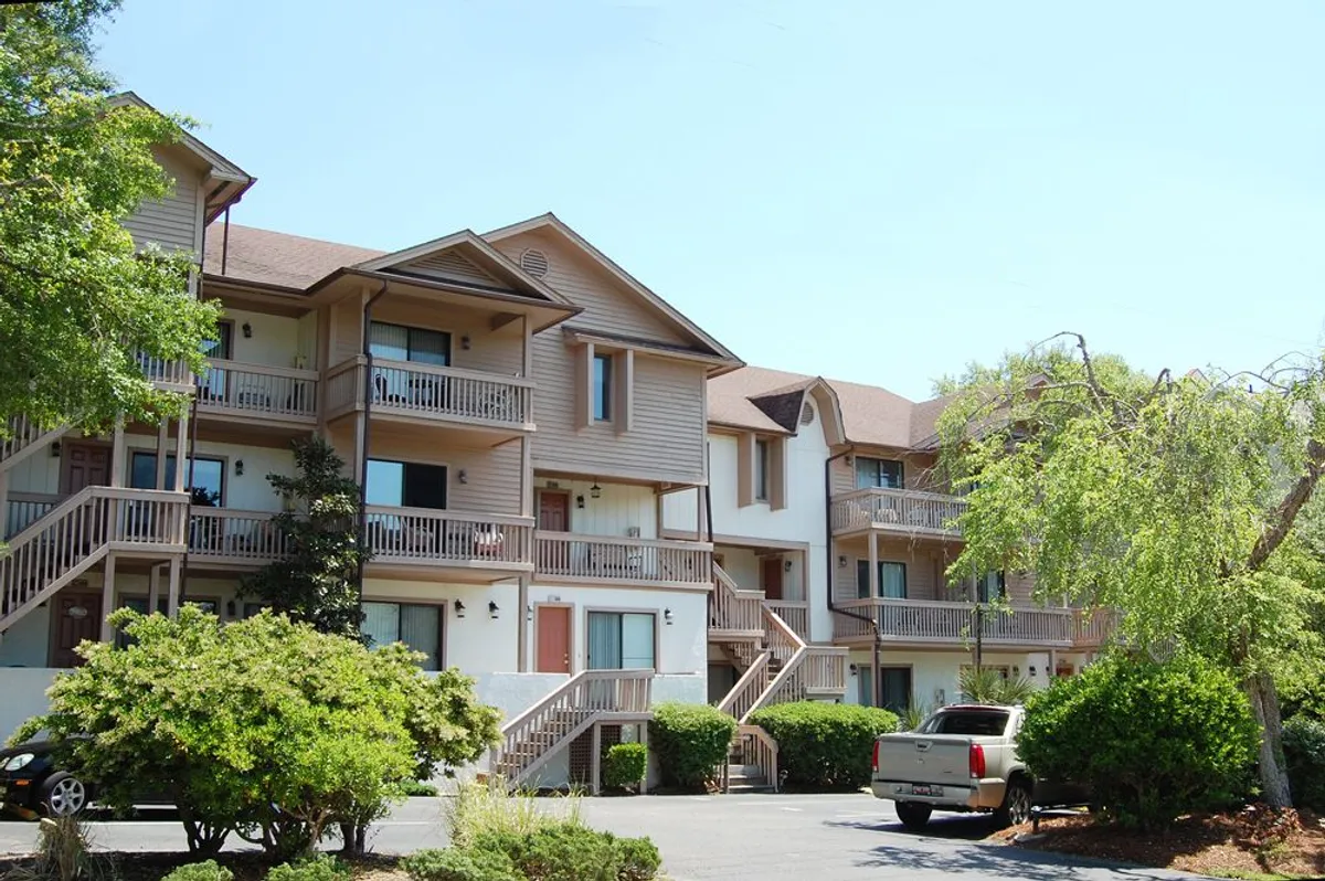 The multi-story building of Harbourside with private balconies and landscaped shrubs in the foreground, suggesting a peaceful and inviting resort setting.