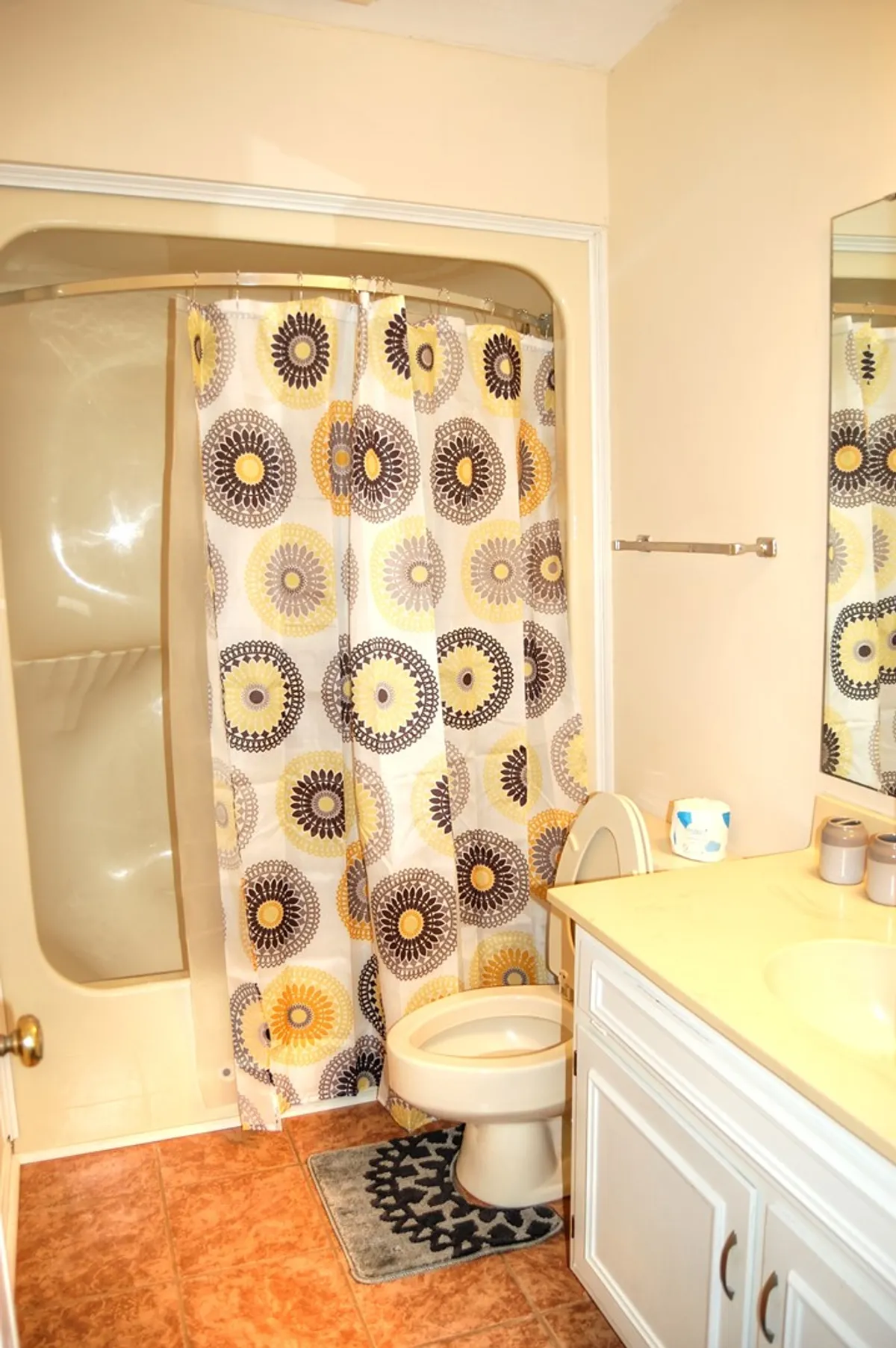 A neat and tidy bathroom with a shower curtain, vanity, and mirror. The neutral tones and uncluttered surfaces emphasize a space ideal for personal grooming and unwinding at the end of the day.