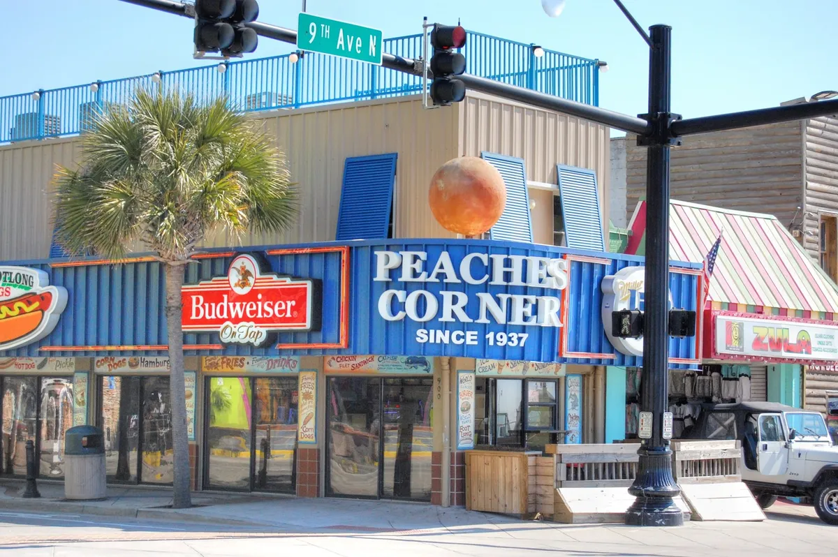 A vibrant scene featuring the iconic Peaches Corner sign, colorful building facades, and a palm tree, all reflecting the lively dining and social atmosphere of Myrtle Beach.